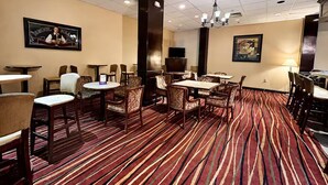 A hotel lobby with multiple seating areas, a television, and a patterned carpet.