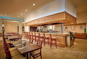 A hotel dining area with multiple tables and chairs, a central bar, and a kitchen area. - 2710i Lakefront 2 Master Pool Spa Disney/Universal (Kissimmee)