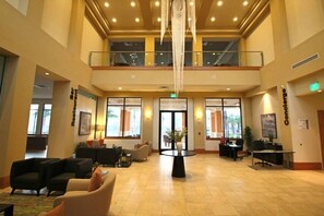 A spacious lobby with a high ceiling, a central chandelier, multiple seating areas, and large windows. - 2710i Lakefront 2 Master Pool Spa Disney/Universal (Kissimmee)