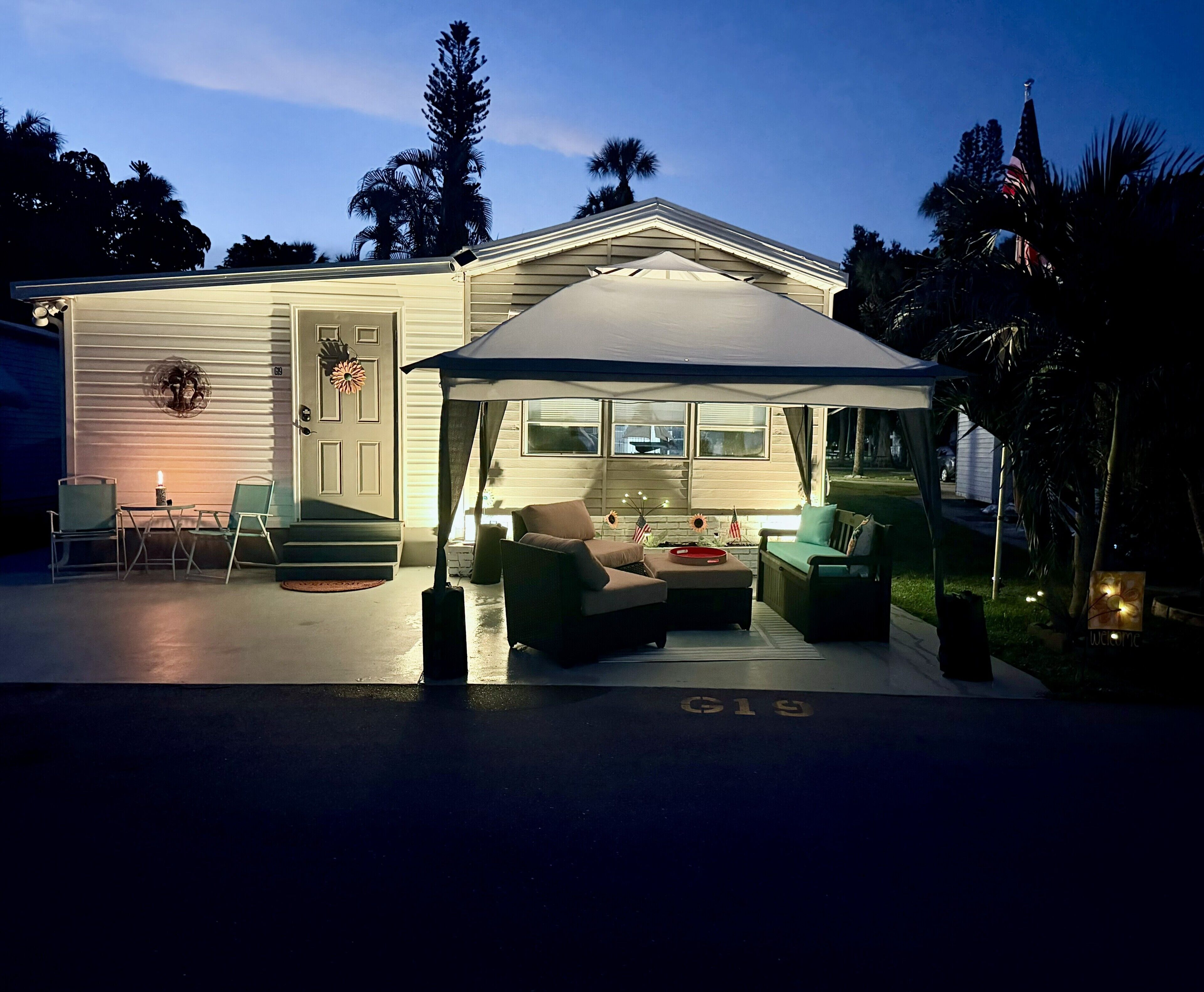 A house with a covered patio area featuring outdoor furniture and a flag.