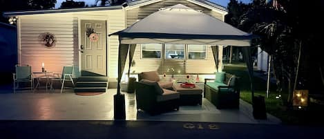 A house with a covered patio area featuring outdoor furniture and a flag.