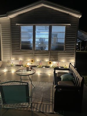 A house with a patio area featuring a table, chairs, and a bench.