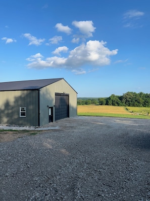 Un bâtiment doté d’un grand portail de garage, d’une petite fenêtre et d’une allée gravillonnée.