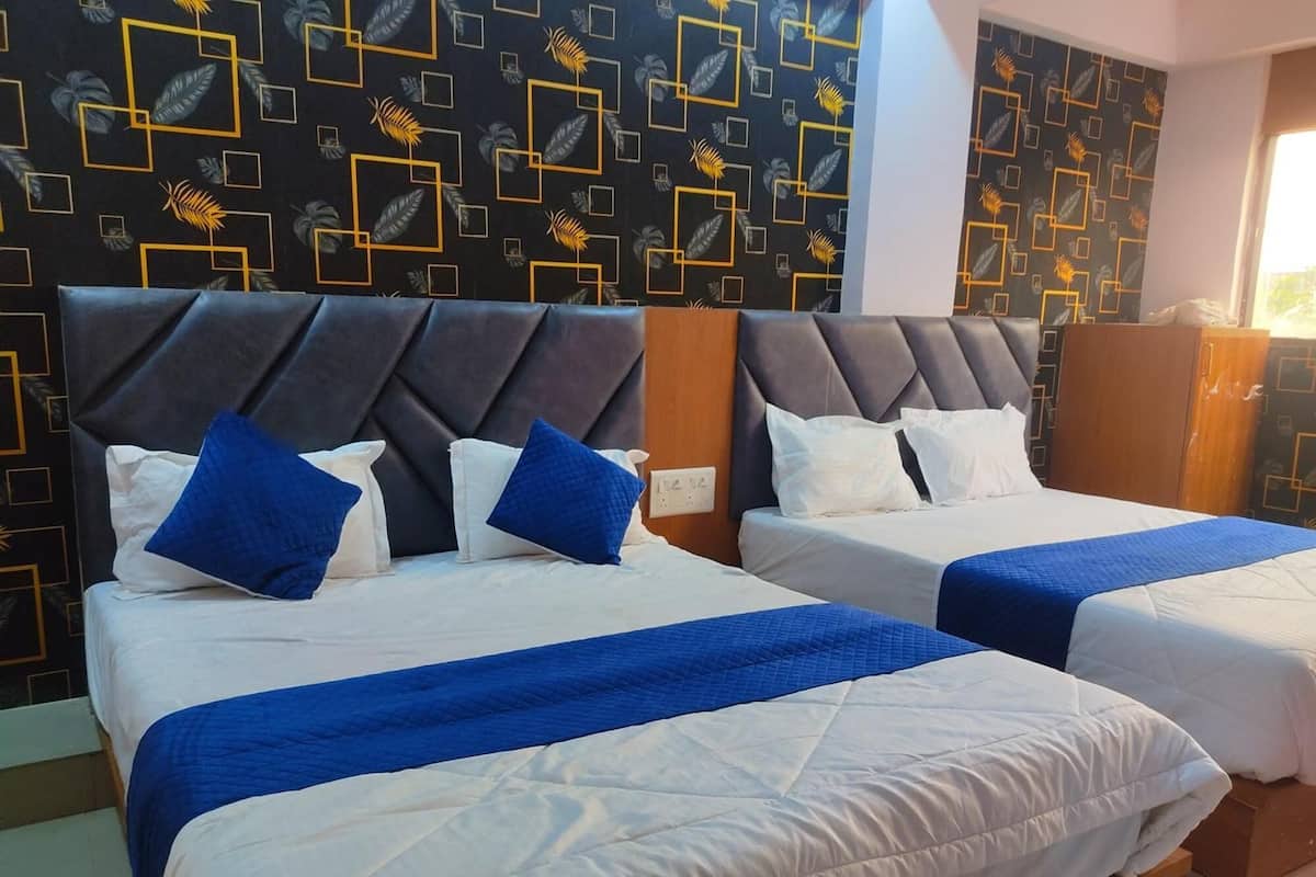 Two beds with headboards, a patterned wall, and a window.