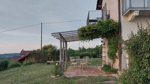 Un patio con una pergola, arredi da esterno e vista su una collina.
