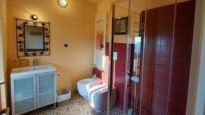 Un bagno con lavandino, specchio, WC e doccia.