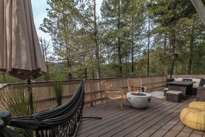 Eine Holzterrasse mit Gartenmöbeln, einer Hängematte und einem Feuerkorb.
