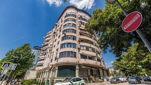 Un edificio de varios pisos con fachada curva, señal de paso para peatones y señal de prohibido el acceso.