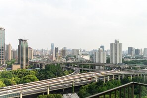 A cityscape with multiple high-rise buildings, a complex highway interchange, and greenery. - Yidu Home -People's Square Branch (Shanghai)