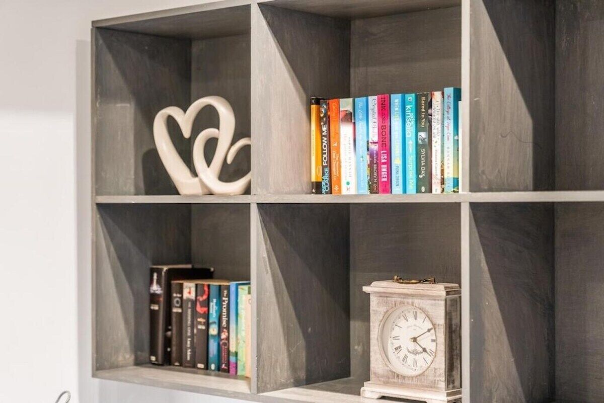 Estante com livros e um objeto decorativo em formato de coração.
