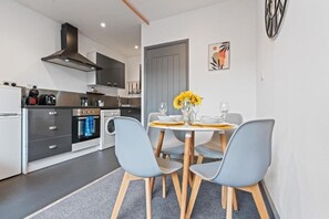 Una cocina moderna con comedor, que incluye una mesa redonda con sillas, horno empotrado y lavadora.