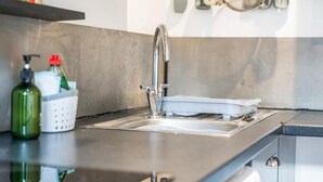 Ett modernt kök med en diskho i rostfritt stål, en tvåldispenser och ett diskställ.
