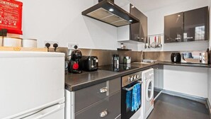 Ett kompakt kök med en inbyggd tvättmaskin, en kaffebryggare och en brödrost.