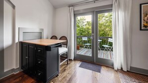 Ein kleines Zimmer mit einer Küchenzeile, einer Schiebetür zum Balkon und einer kleinen Essecke.