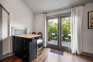 A compact room with a kitchenette, a sliding glass door to a balcony, and a small dining area. - Guest Suite | Private Entrance and Balcony (Nashville)