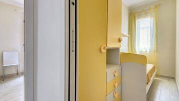 Una stanza arredata con un letto, una sedia, un armadio e una finestra con tende.