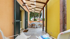 A covered patio with a table and chairs, a hammock, and a magazine on a chair.