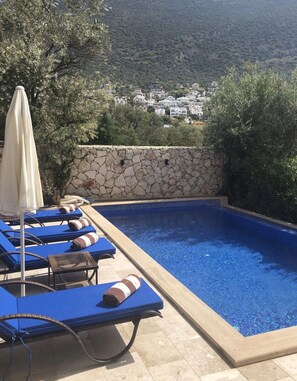 Ein Pool im Freien mit Liegestühlen und einer Steinmauer.