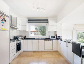 Eine moderne Küche mit weißen Schränken, einem Herd, einer Mikrowelle und einem Fenster.