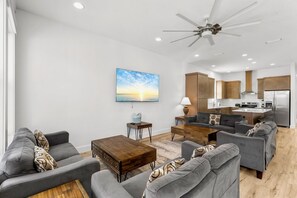 Ein modernes Wohnzimmer mit grauen Sofas, einem Holztisch und einem Gemälde von einem Sonnenuntergang.