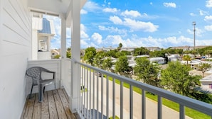 Un balcon donnant sur un quartier résidentiel, une chaise et une rambarde.
