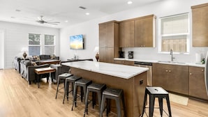 Une cuisine moderne dotée d’un îlot central, de tabourets de bar et d’un coin repas comprenant un canapé et des chaises.