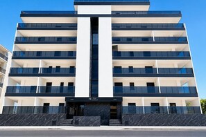 A multi-story building with a central entrance, balconies on each floor, and a clear sky. - GuestHost - Perla Nera Apartment 3 near the sea (Trani)
