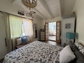 A bedroom with a bed, a dresser, a mirror, and a door leading to another room. - Cozy Foothill retreat in serene Tujunga (Tujunga)