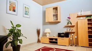 Ein Wohnzimmer mit einem Holzkabinett, einem Blumentopf, einer Lampe und einem roten Teppich.
