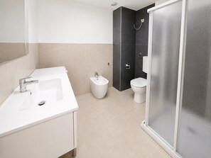 Ein modernes Badezimmer mit Waschbecken, Bidet, Toilette und einer Duschkabine aus Glas.