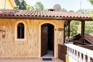 Un bâtiment en bois avec un toit recouvert de tuiles, une porte et un petit balcon.