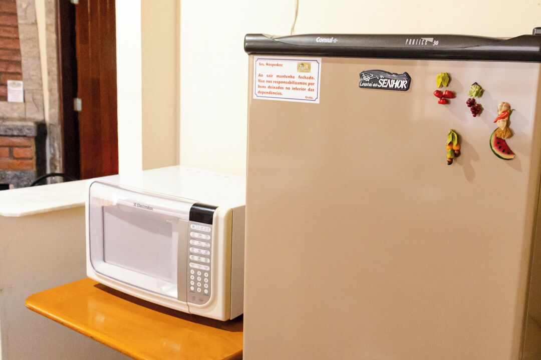 Una cocina con microondas y refrigerador, una encimera de madera, y una puerta con un cartel.