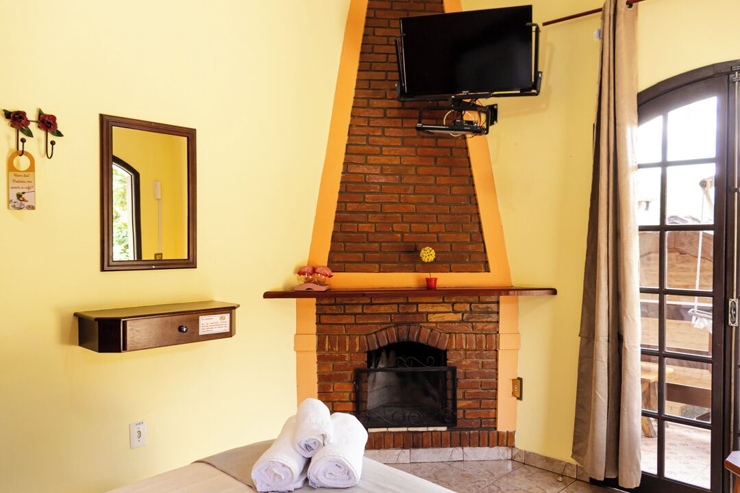 A room with a brick fireplace, a television mounted above it, a mirror on the wall, and a door leading outside.