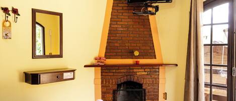 A room with a brick fireplace, a television mounted above it, a mirror on the wall, and a door leading outside.