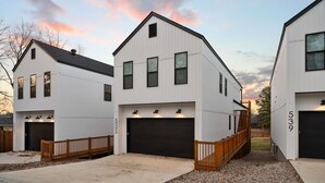 Ein modernes Wohngebäude mit Garage, Holzterrasse und Schotterauffahrt.