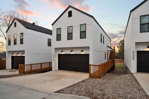 Ein modernes Wohngebäude mit Garage, Holzterrasse und Schotterauffahrt.