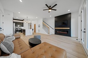 Ein modernes Wohnzimmer mit einer Couch, einem Hocker und einem Kamin.