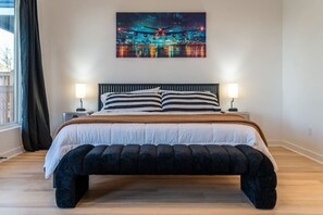 Ein modernes Schlafzimmer mit einem großen Bett, einem Kopfteil, Nachttischlampen und einem Stadtbild über dem Bett.