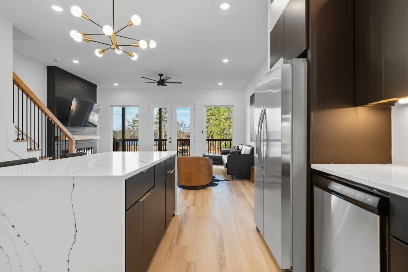 A modern kitchen with a marble countertop, stainless steel appliances, and a ceiling fan.