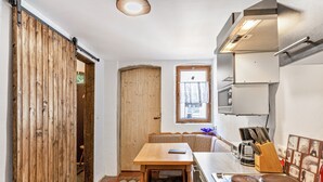Una cocina compacta con una mesa de madera, una ventana y una puerta corrediza.