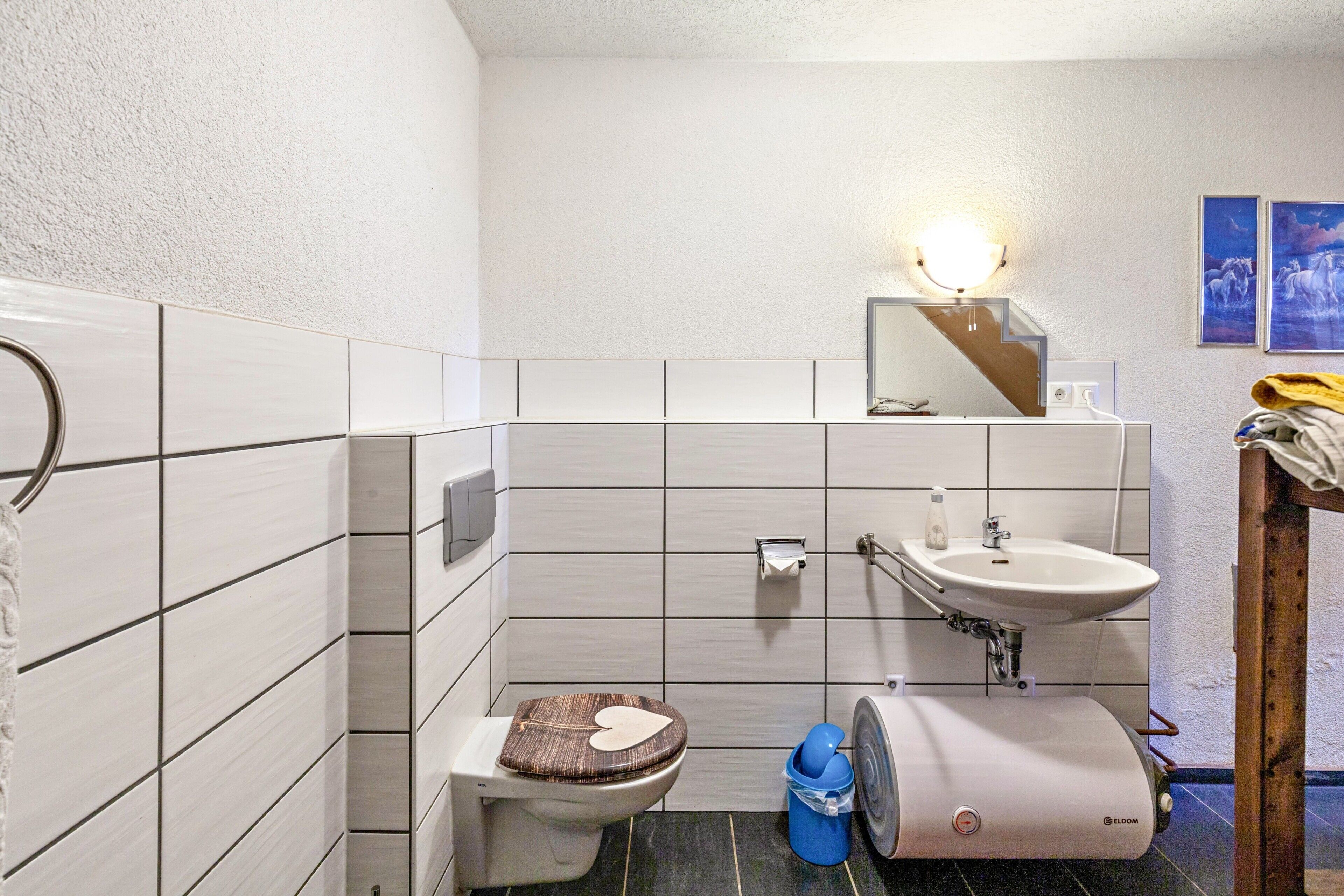 Een badkamer met toilet, wastafel en spiegel.