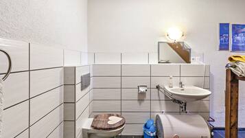 Een badkamer met toilet, wastafel en spiegel.
