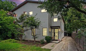 Ein modernes, zweistöckiges Haus mit befestigter Auffahrt, einem kleinen Garten und einem Holzzaun.