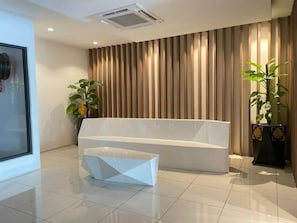 A reception area with a modern reception desk, a large potted plant, and a vertical striped wall.
