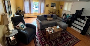 A living room with a sofa, armchair, and a small table with magazines.