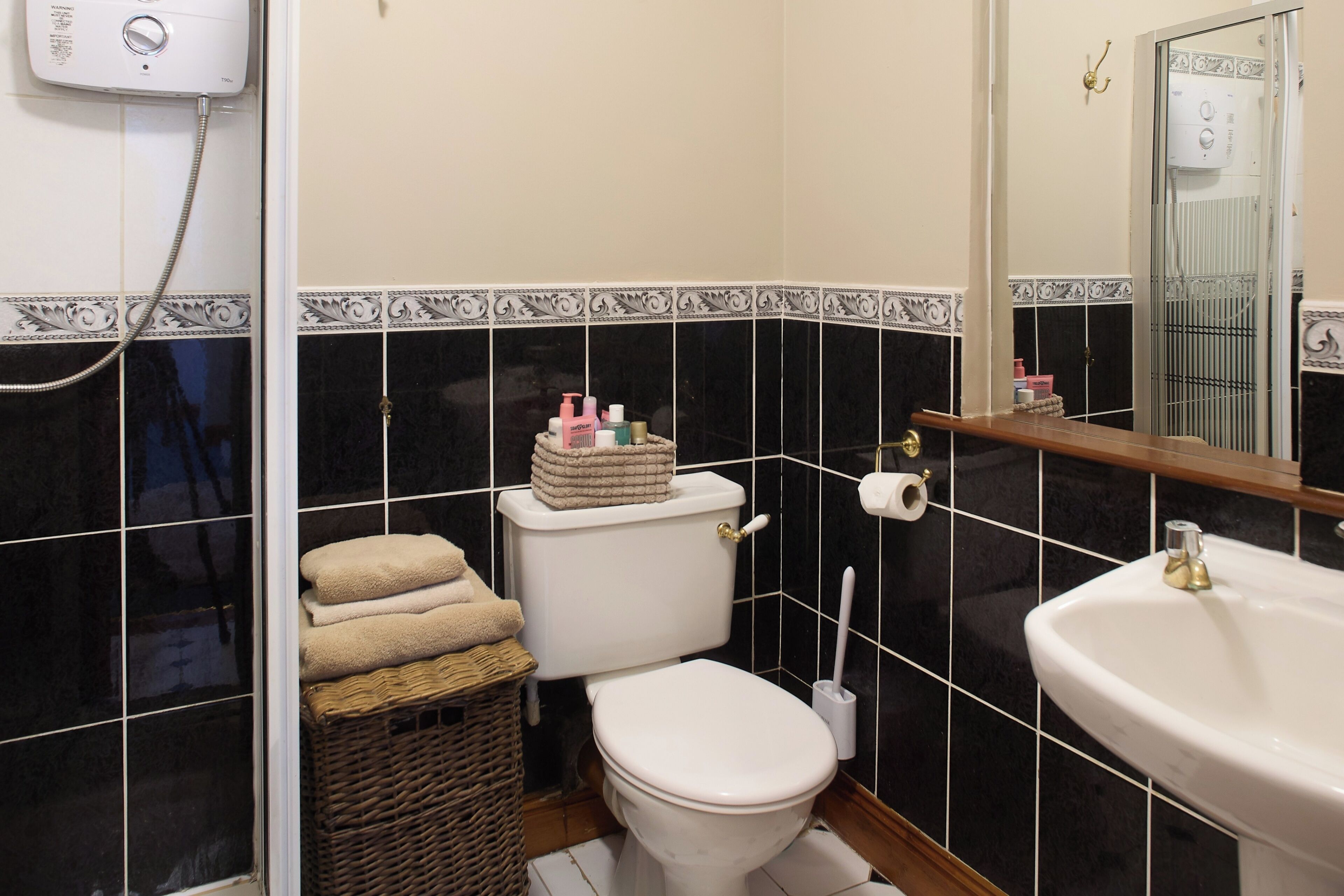 Een badkamer met toilet, wastafel, spiegel en douche.