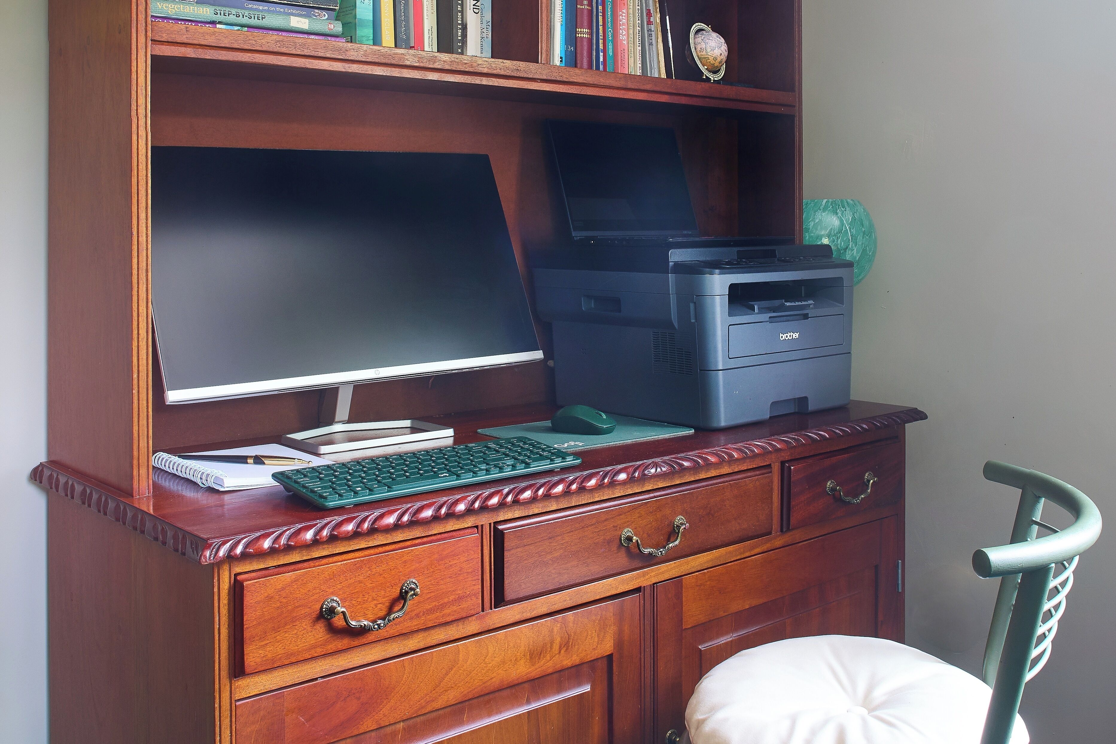 Un escritorio de madera con una computadora de escritorio, una impresora y una silla.