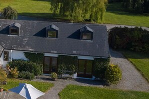 Une maison à deux étages, dotée d’un toit en pente, d’un porche à l’avant et d’un petit jardin.