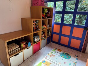 A room with a wooden bookshelf, a door with a blue frame, and a window with a view of greenery. - Family Getaway in Santa Elena (Antioquia)