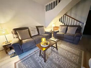 A living room with a sofa, a coffee table, and a staircase.